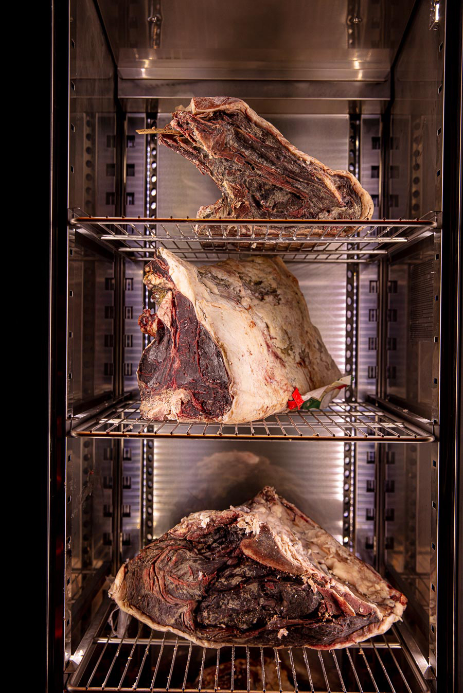 A rack of assorted meats displayed in a refrigerator, highlighting offerings for Butchery and Barbecue Masterclasses