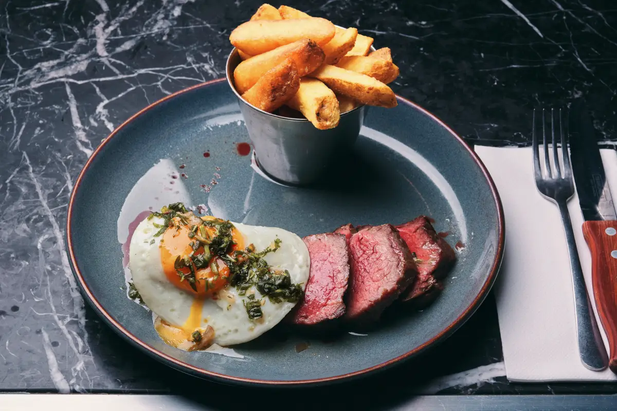 A plate featuring steak and eggs alongside crispy fries