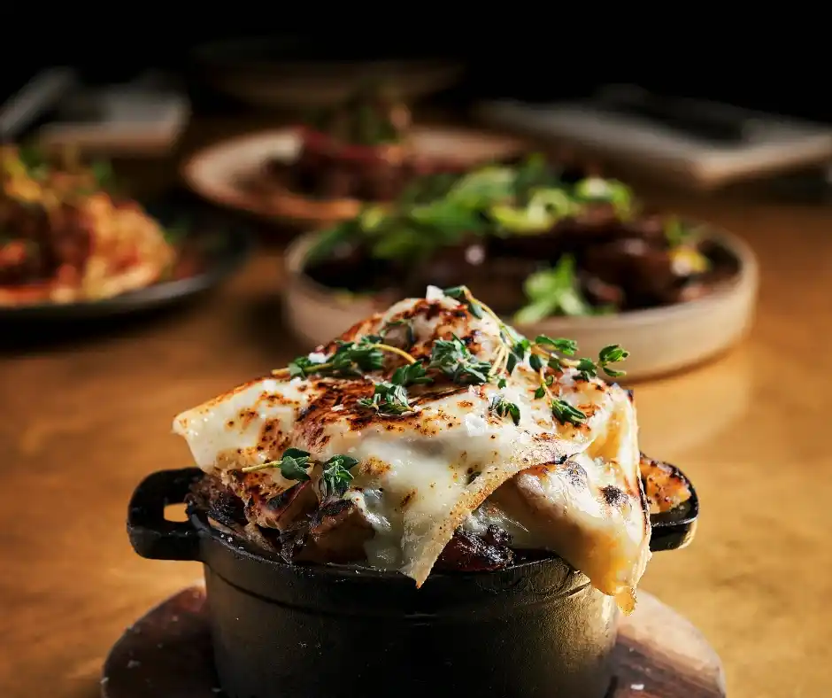 A black pot filled with melted cheese and herbs sits on a table at Temper Restaurant, a Central London steakhouse