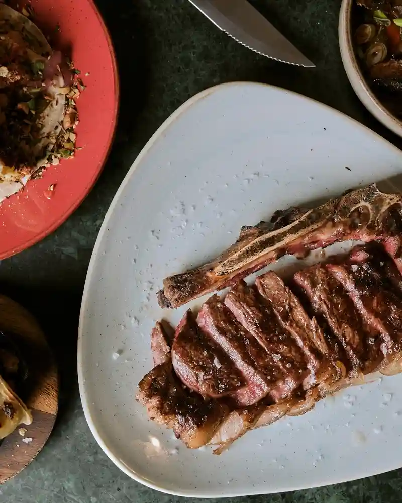 A perfectly cooked steak on a plate accompanied by a serving of fluffy rice, showcasing Temper Restaurant's culinary offerings