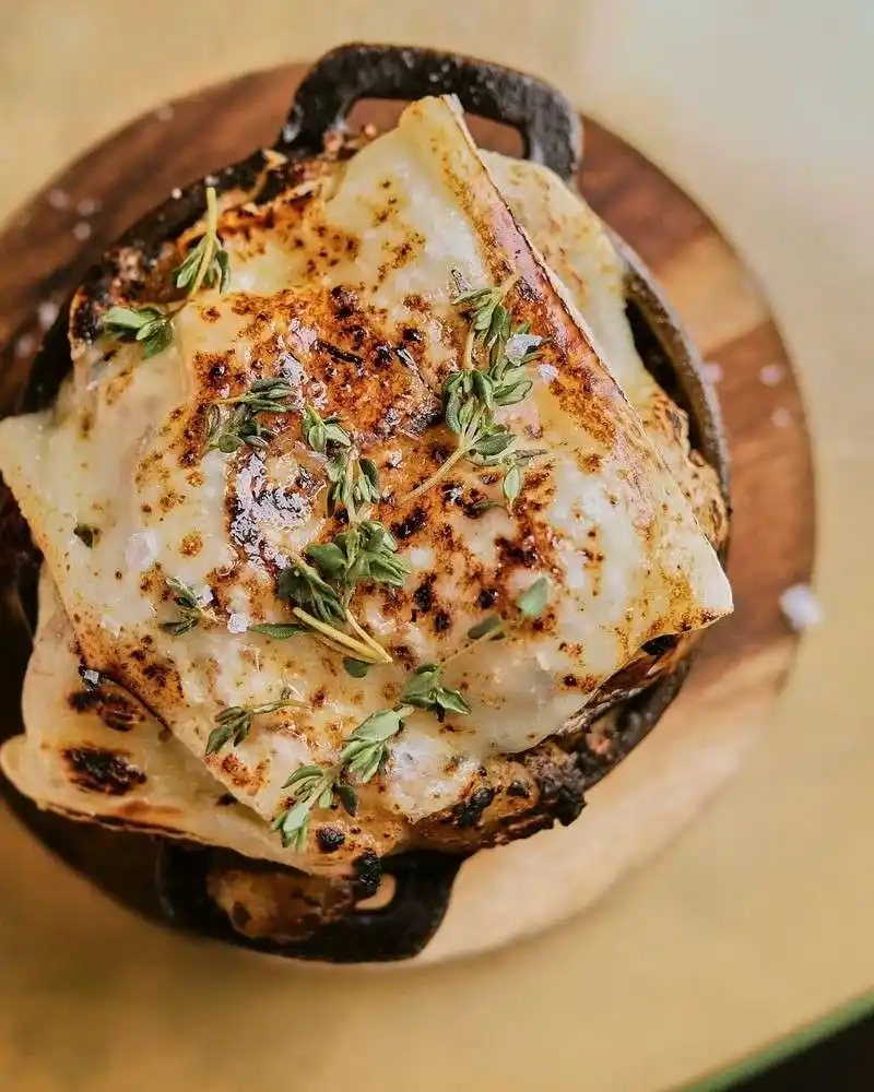 A beautifully arranged plate of cheese topped with vibrant herbs, highlighting the culinary offerings of Temper Restauran