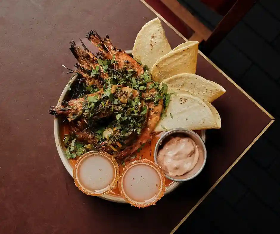 A plate featuring shrimp, crispy chips, and vibrant salsa, served at Temper Restaurant in Central London