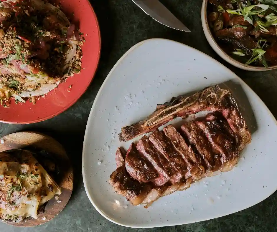 . A dining table featuring steak, potatoes, and assorted dishes, showcasing the offerings of Temper Restaurant in London